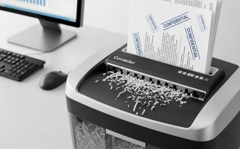 Modern office paper shredder destroying confidential business documents into small particles for security protection